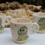 Tasse pour enfant en faïence blanche,décorée de deux bébés dragons et des petits coeurs de couleur à l'intérieur