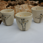 tasse pour enfant en faïence blanche,décorée de trois girafes et de petits pois de couleur à l'intérieur