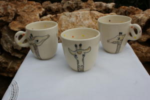 tasse pour enfant en faïence blanche,décorée de trois girafes et de petits pois de couleur à l'intérieur